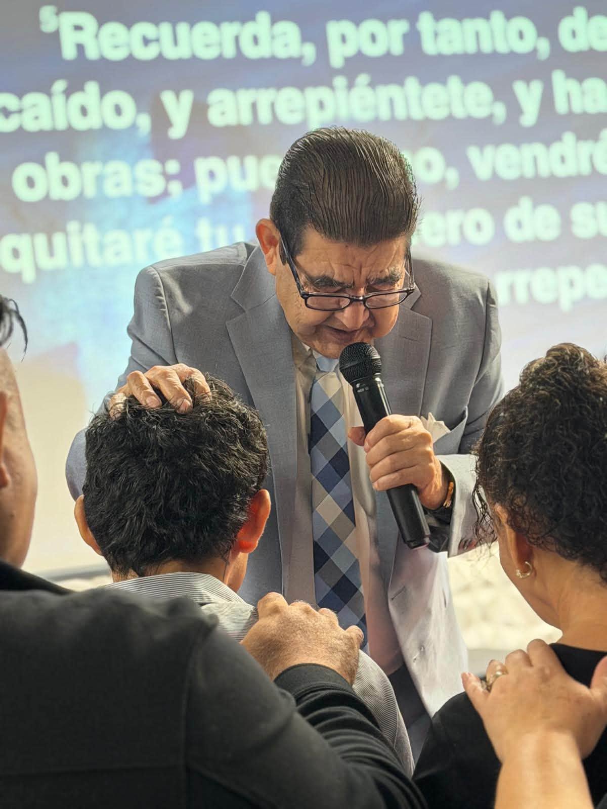El pastor orando con miembros de la congregación